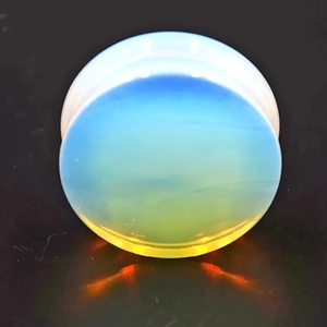 Macro shot of circular opal ear plug with vibrant fire effect on a black background