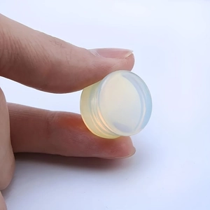 Polished translucent white opal glass ear plugs gauges held to show scale and size