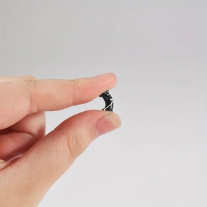 Zwarte siliconen oor expander tussen vingers om de microgrootte en zachte textuur te tonen
