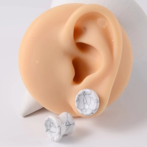 Vue détaillée des écarteurs en turquoise blanche sur un modèle d'oreille en silicone