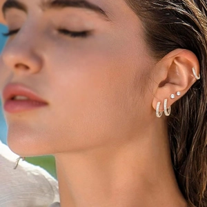Close-up of stacked stainless steel hoop earrings and cz studs on a female ear