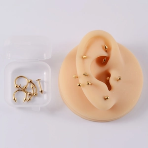 Set di piercing in acciaio dorato su modello di orecchio in silicone con custodia
