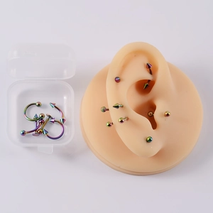 Set piercing in acciaio inossidabile arcobaleno con custodia mostrata su modello orecchio