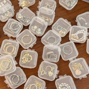 Detailed view of assorted gold and silver jewelry organized in mini clear plastic boxes