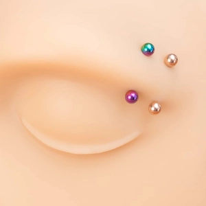 Detail showing colorful stainless steel piercing balls on a silicone model