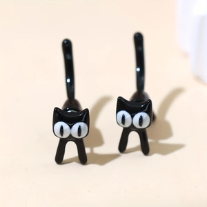 Primer plano de pendientes creativos de gato negro en acero inoxidable pulido