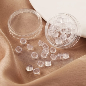 Macro view of transparent silicone hamburger ear backings in a clear storage box