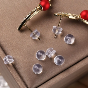 Detailed macro view of clear silicone earring backings and gold earrings on silk surface