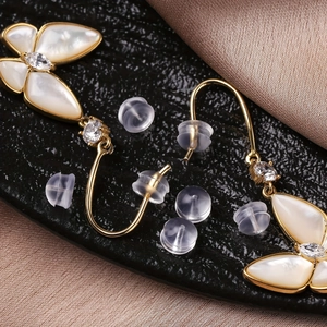 Macro shot of butterfly earrings with white shell wings and clear silicone earring backs