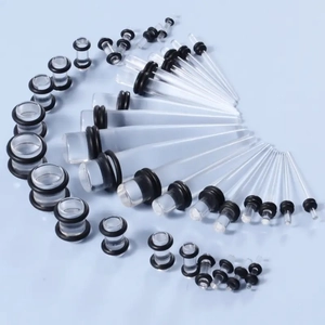 Flat lay detail of clear acrylic ear stretching kit with black O-rings on blue background