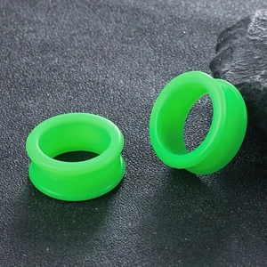 Nahaufnahme neongrüner Silikon Ear Tunnel mit Double Flare auf schwarzem Stein