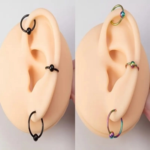 Set aus schwarzen und regenbogenfarbenen 16G Edelstahl-Piercings an Silikon-Ohrmodellen