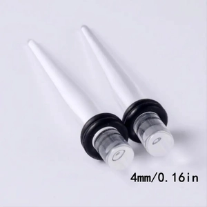 Detail of 4mm white acrylic ear tapers with black rubber O-rings on plain background