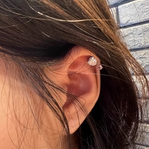 Detail of horseshoe cartilage stud with sparkling clear and purple cubic zirconia