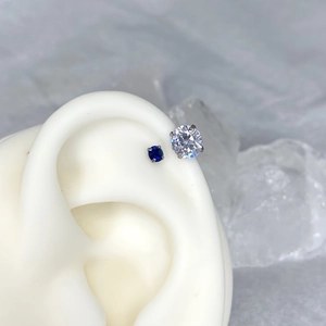 Macro shot of cubic zirconia stud earrings in blue and white on a silicone ear model