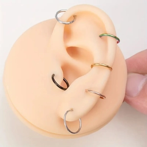 Detail showing colorful 316L stainless steel seamless rings on a silicone ear model