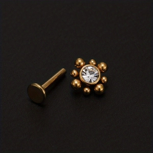 Piercing labret dorato con fiore di zircone per orecchio e labbra su sfondo nero liscio