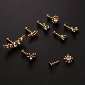 Vista macro di piercing labret dorati con zirconi bianchi in vari design per orecchio