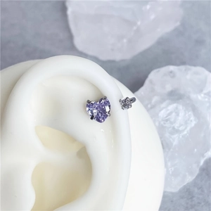 Macro shot of heart-shaped lavender zircon earring set on a white silicone ear model