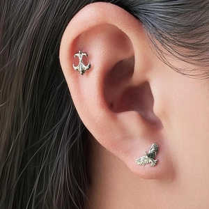 G23 titanium ear studs featuring silver fleur-de-lis and eagle designs for ear piercings