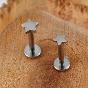 Macro detail van G23 titanium ster labret piercings met platte basis op hout