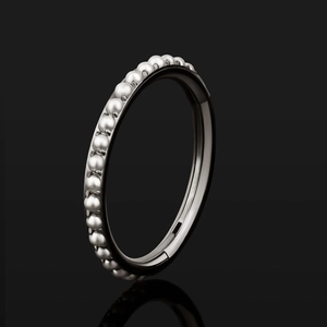 Anillo clicker de titanio ASTM F136 con fila de perlas blancas sobre fondo negro