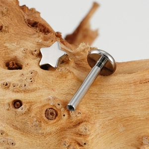 Gepolijste G23 titanium labret piercing met ster en interne schroefdraad op hout