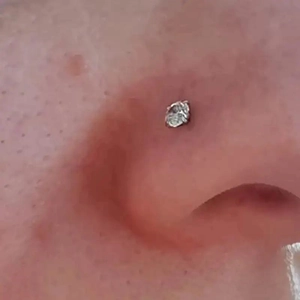 Dettaglio di un piercing al naso minimalista in acciaio inossidabile 20G con zircone lucido