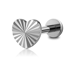 Macro detail of silver heart cartilage stud with radial texture and flat back post