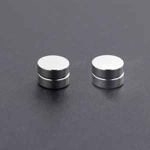 Close-up of small silver cylindrical magnetic earrings with smooth metallic finish