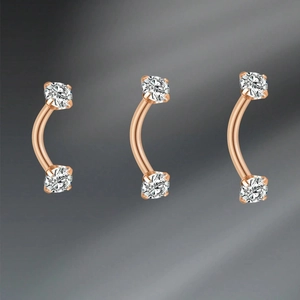 Detailed macro view of three rose gold curved barbells with sparkling zircon stones