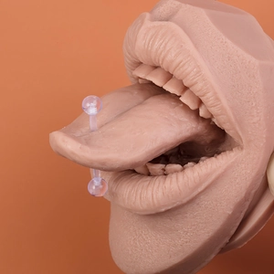 Macro view of transparent acrylic tongue barbell piercing on a realistic silicone model