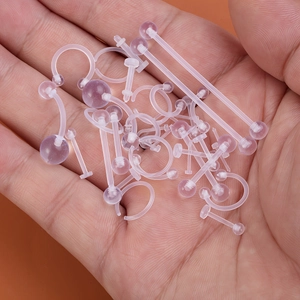 Detailed view of clear pink acrylic body piercing jewelry set held in hand for size
