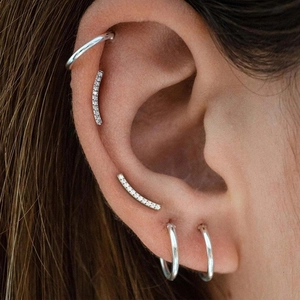 Close-up of G23 titanium silver earrings set with studs and hoops for cartilage piercing