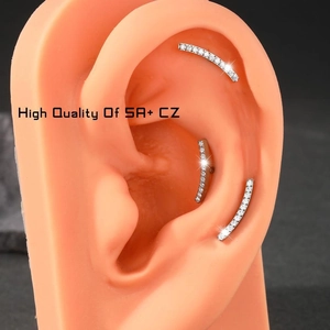 Macro view of G23 titanium curved cartilage earrings with 5A+ CZ studs on an ear model