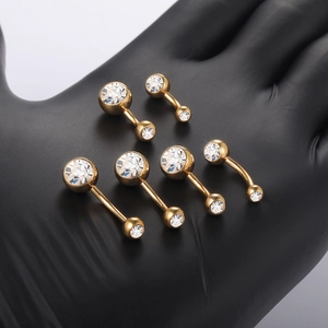Detailopname van gouden titanium navel piercings met 5A zirkonia stenen op de hand