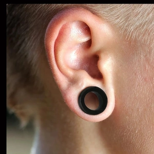 Tunnels d'oreille évasés en silicone noir flexible portés sur le lobe de l'oreille