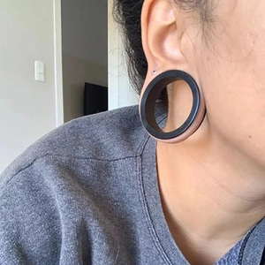 Détail macro d'un large tunnel d'oreille en silicone noir flexible porté sur l'oreille