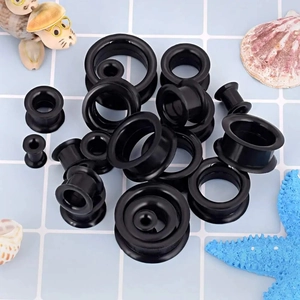Vue macro de tunnels d'oreille en silicone noir souple de différentes tailles sur carreaux bleus