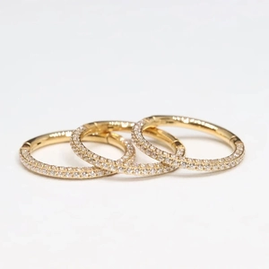 Three golden ASTM F136 titanium clicker rings with micro-pave CZ stones on white background