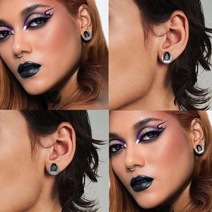 Detail of gothic stainless steel ear plugs with skull hand and gravestone cross patterns