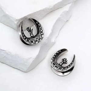 Macro detail of silver gothic U-shape ear gauges with vintage claw and stitch textures