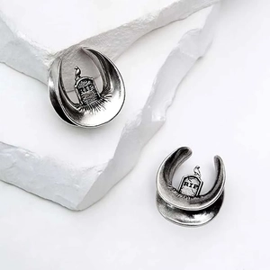 Detailed macro view of vintage silver gothic ear plugs with RIP tombstone and bird design