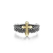 Macro detail of gothic silver wing ring featuring a central gold cross with vintage finish