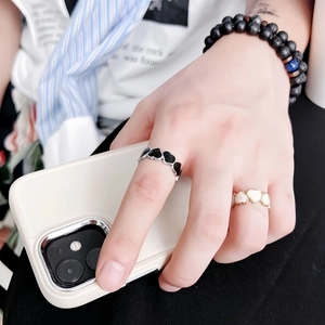 Detail shot of heart-shaped rings and black matte beaded bracelet on hands