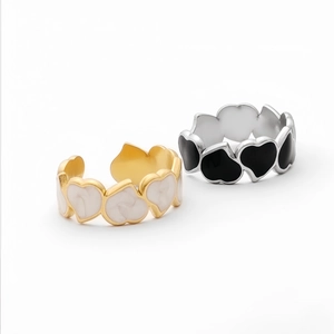 Detail of gold and silver heart rings with white and black enamel inlay and polished finish