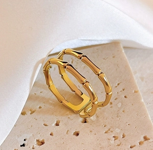Macro shot of gold double-layer bamboo joint ring on stone background with silk