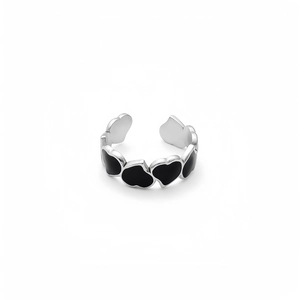 Detailed shot of open adjustable ring with black enamel heart patterns on silver metal