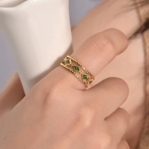 Detail of vintage golden twisted rope ring with green enamel rhombuses on a model hand