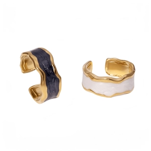 Gold-plated wavy rings with black and white marble enamel finish on a clean background